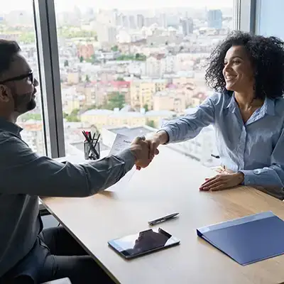 two people shaking hands across a table.