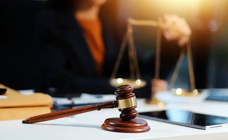 A woman with scale and a gavel next to her on the desk..